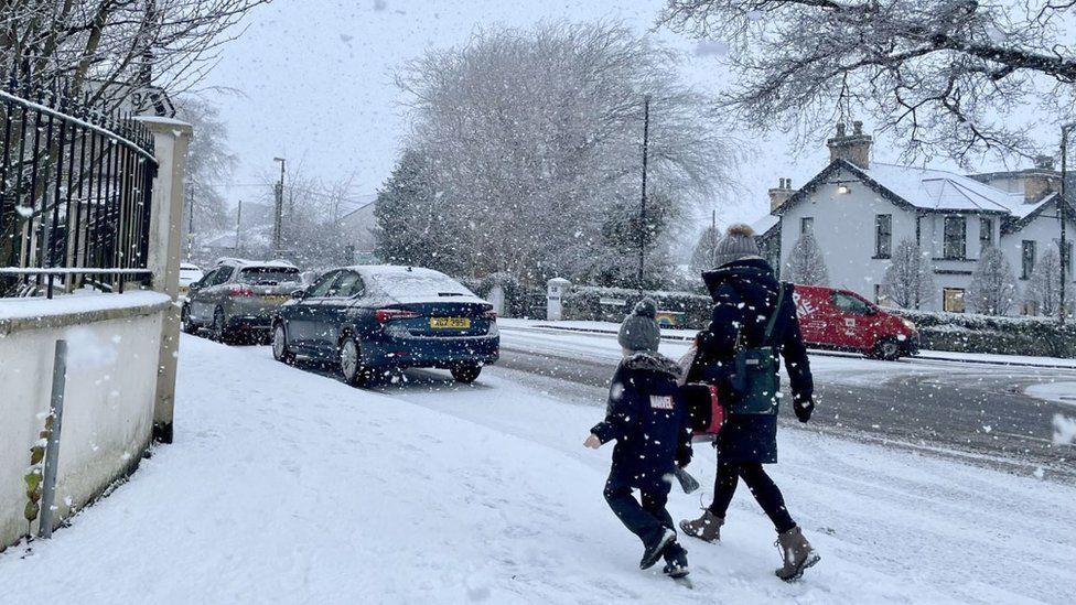 A woman and a child walk through snow in Eglinton, Northern Ireland