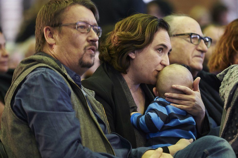 Ada Colau (C), kisses her baby next to Xavier Domenech (L), Catalunya en Comu's candidate for the regional election, 11 November 2017