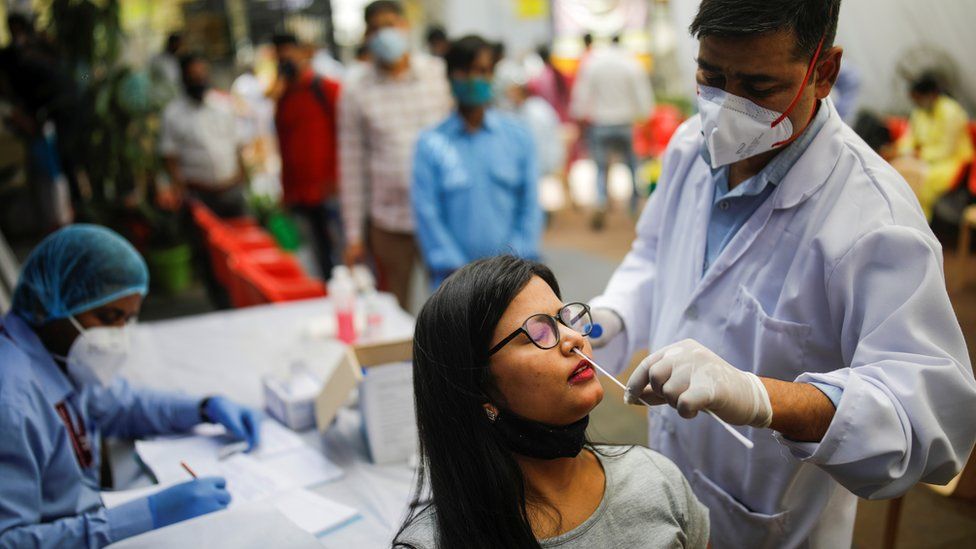 A healthcare worker collects a swab sample from a woman
