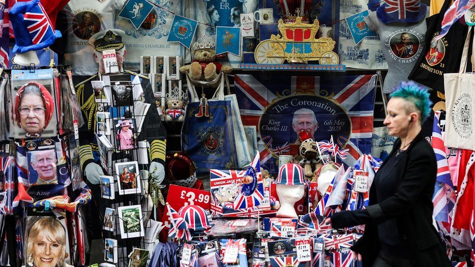 A woman with spiky blue hair walks past a gift shop during Coronation week in Windsor