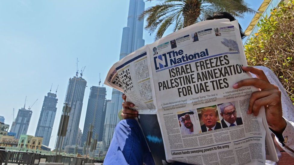 A man reads a copy of UAE-based The National newspaper near the Burj Khalifa, the tallest structure and building in the world since 2009, in the gulf emirate of Dubai on August 14, 2020, as the publication's headline reflects the previous day's news as Israel and the UAE agreed to normalise relations in a landmark US-brokered deal.