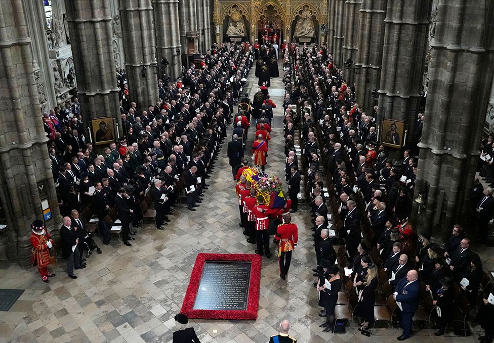 A Bearer Party of The Queen's Company, 1st Battalion Grenadier Guards carries the coffin of Queen Elizabeth II, draped in the Royal Standard, into Westminster Abbey in London on September 19, 2022, ahead of the State Funeral Service. - Leaders from around the world will attend the state funeral of Queen Elizabeth II