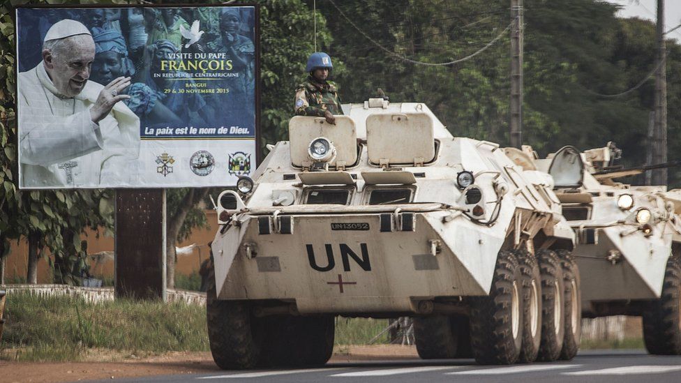 A United Nations Operation in Central African Republic (MINUSCA) military convoy drives by a billboard welcoming Pope Francis ahead of his upcoming visit on November 25, 2015 in Bangui