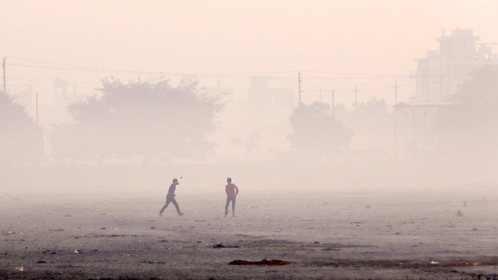 Children playing cricket in smog
