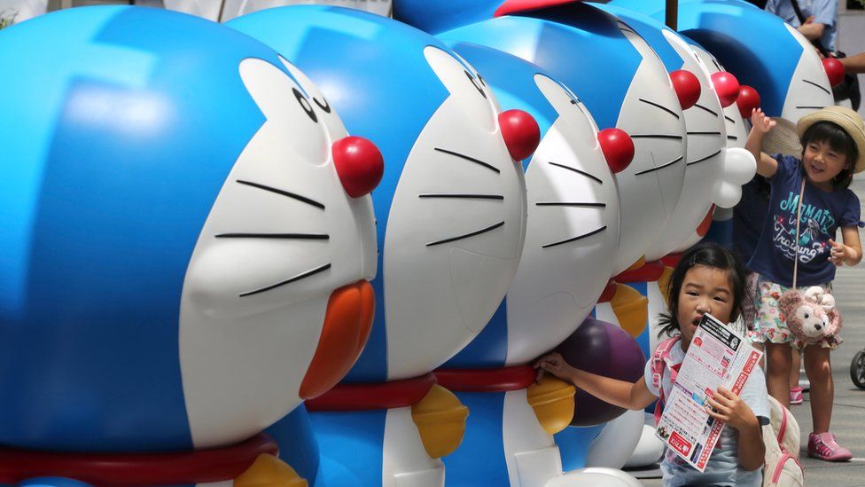 Girls touch models of Doraemon, a Japanese popular animation character, displayed at Tokyo's Roppongi Hills, 30 July 2016.