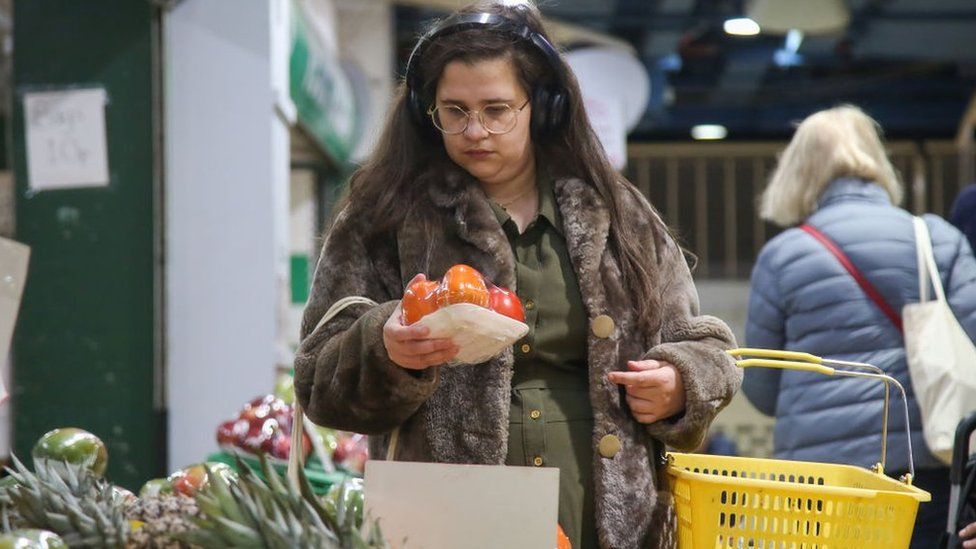 Женщина покупает овощи