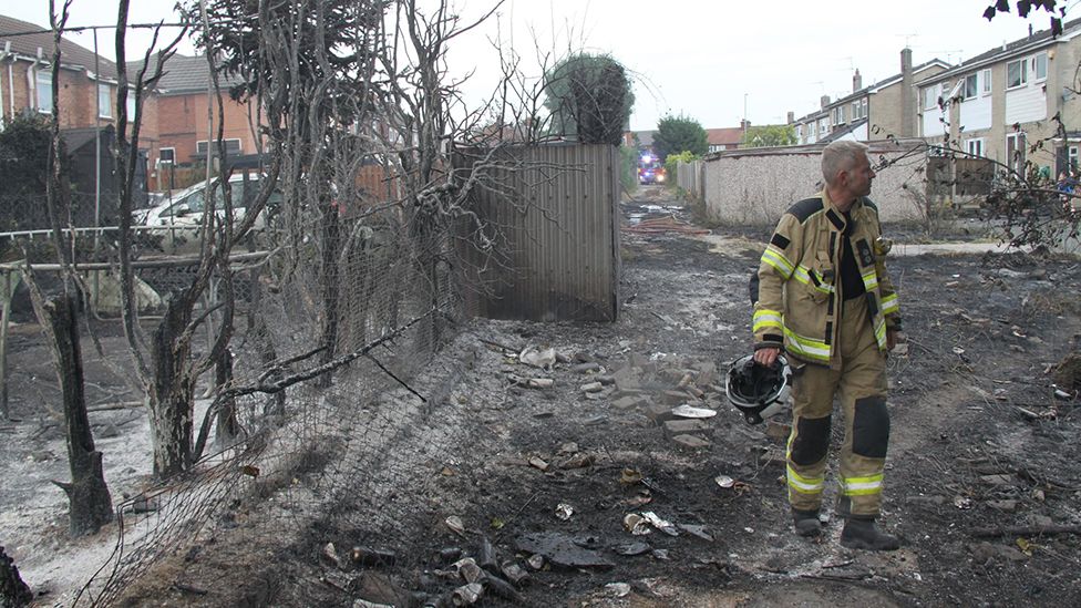 Firefighter walks through burnt-out trees