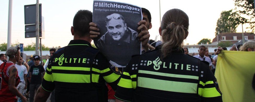 Protester holds up placard of Aruba-born Mitch Henriquez who died in June 2015