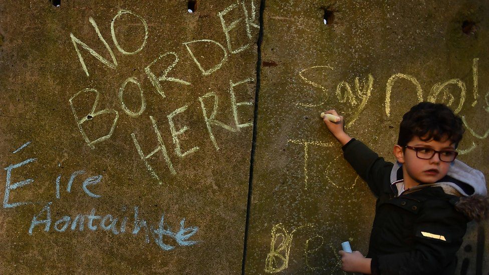 A boy writing anti-Brexit slogans on a wall on the Irish border