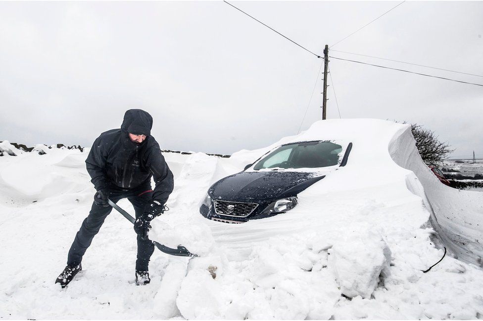 A person digging their car out from under heavy snow