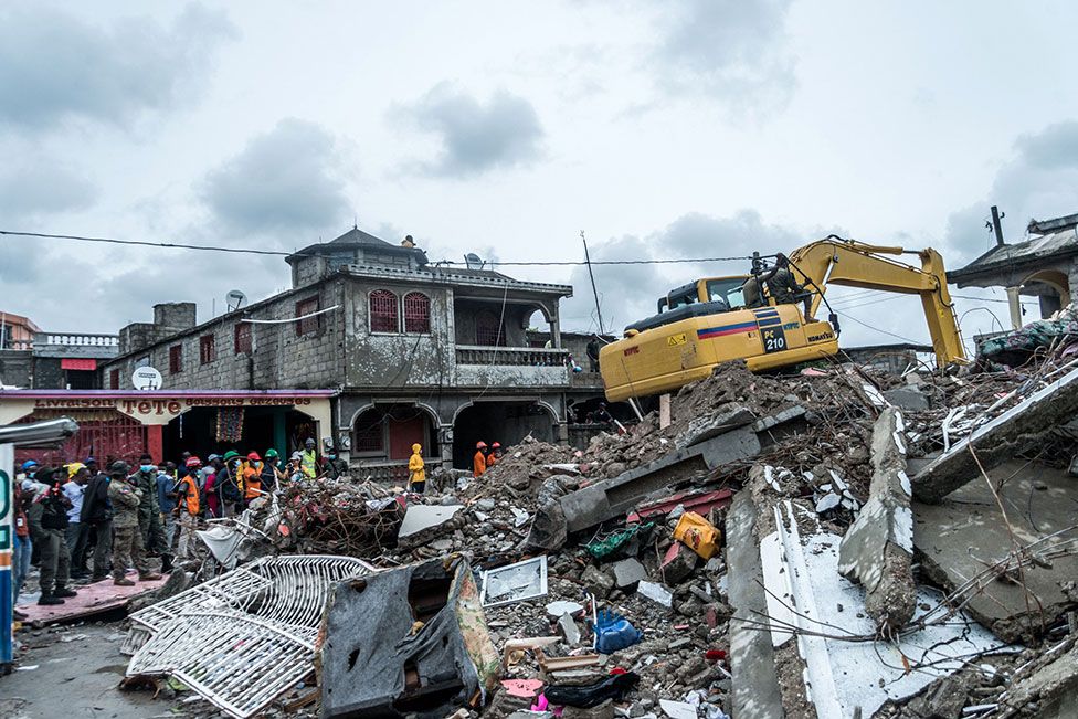 A bulldozer clears the rubble of a building that collapsed in the earthquake in Brefet, a neighborhood of Les Cayes, Haiti, on 17 August 2021