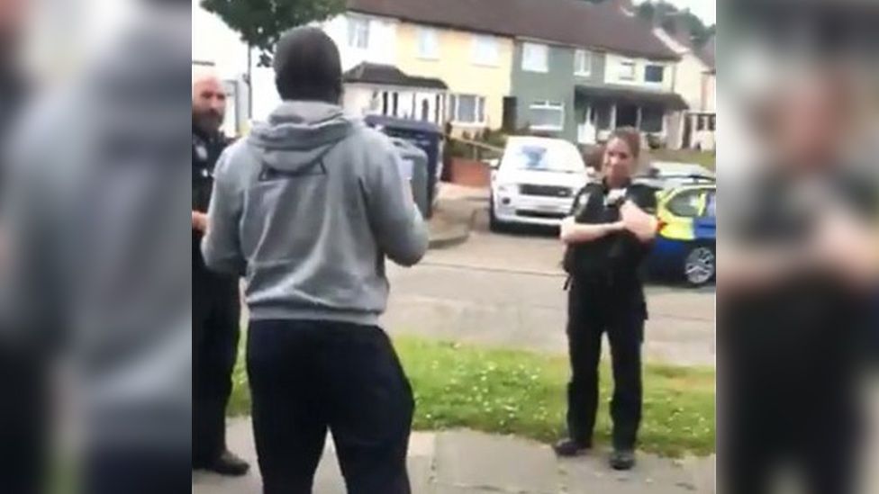 Two white police officers speaking to a black man