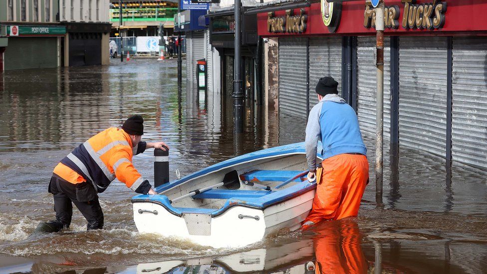 Two men guide a boat through flood waters in Newry
