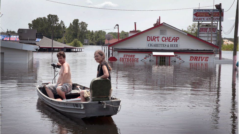 Residents use a boat to get back to a home as floodwater from the Mississippi River continues to rise