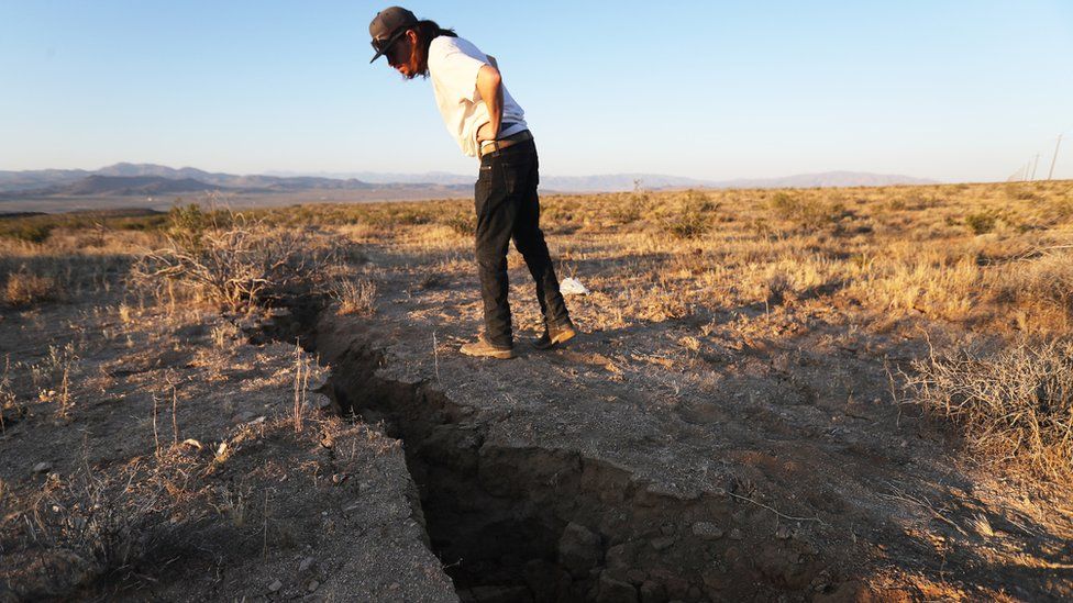 A local resident inspects a crack in the earth