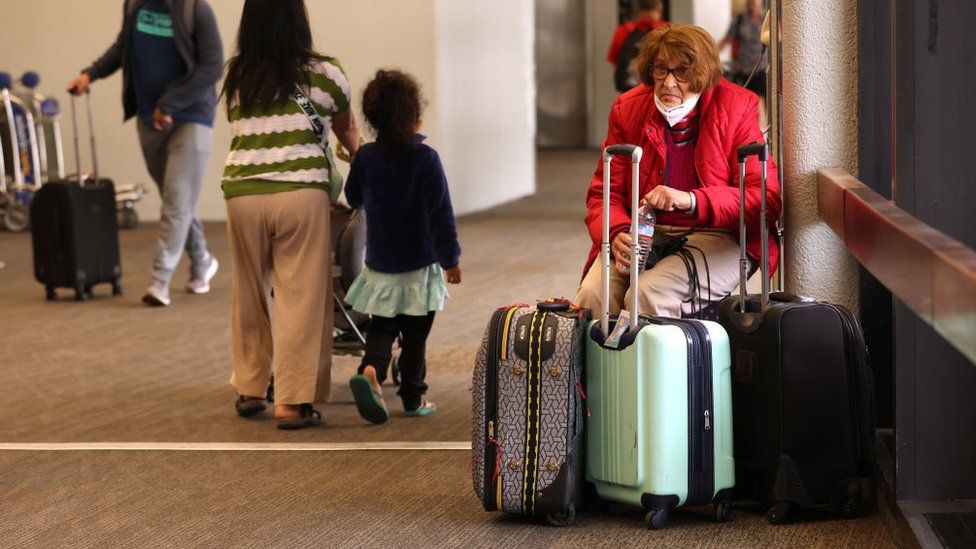A traveler sits with her luggage at San Francisco International Airport on May 12, 2022 in San Francisco, California. According to a report by the Bureau of Labor Statistics, airline fares surged 18.6% in April as demand for air travel has increased due to COVID-19-related travel restrictions being eased