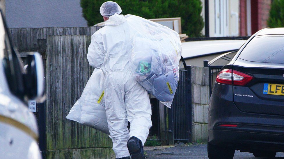 A forensics officer carrying two large bags