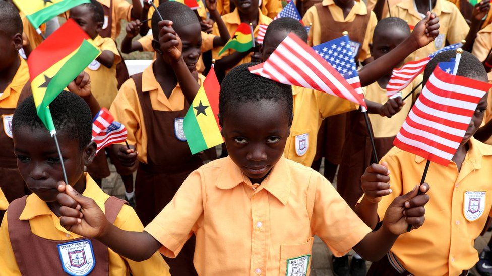 Children carry flags as they greet U.S. first lady Melania Trump on arrival in Accra