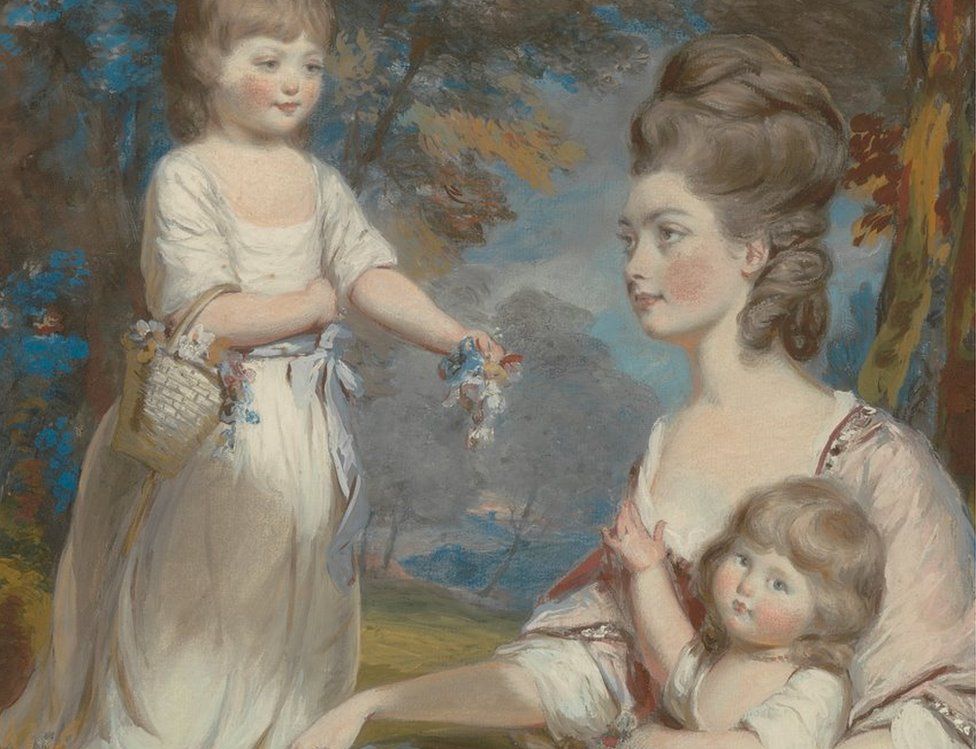 Portrait of an elegant looking woman holding a young child with another young child standing next to her passing flowers from a basket