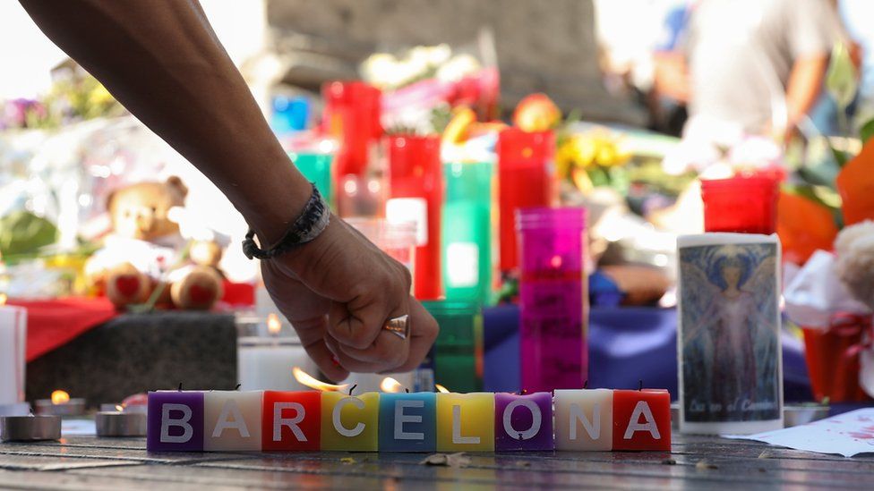 A man lights a candle in an impromptu memorial a day after a van crashed into pedestrians at Las Ramblas in Barcelona