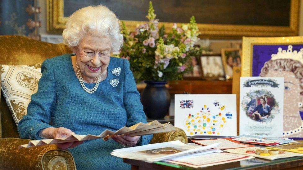 Королева смотрит на веера, рассматривая выставку памятных вещей, посвященных ее золотому и платиновому юбилею
