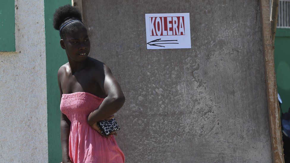 A woman stands next to a sigh at the hospital in Port- Salut, southwest of Port-au-Prince, on 9 October