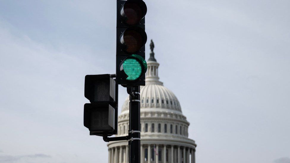 A traffic light with the US congress behind it