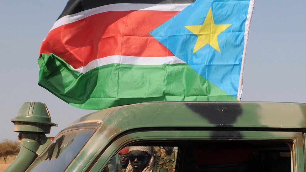 A soldier looking through a military vehicle flying the South Sudanese flag - 2012