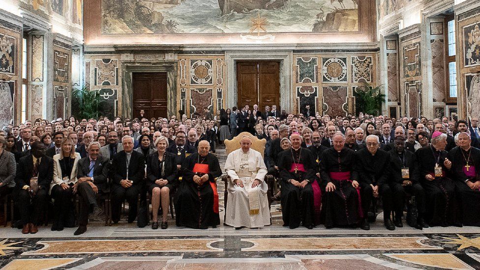 Pope Francis sits in the Apostolic Palace, surrounded by members of the Pontifical Academy of Life