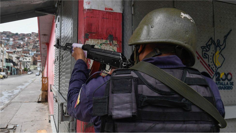 A member of the Bolivarian National Police aims at a possible target after clashes with alleged members of a criminal gang at the Cota 905 neighborhood, in Caracas on July 9, 2021.