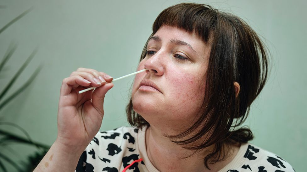 Stock image of a woman using a Covid test swab