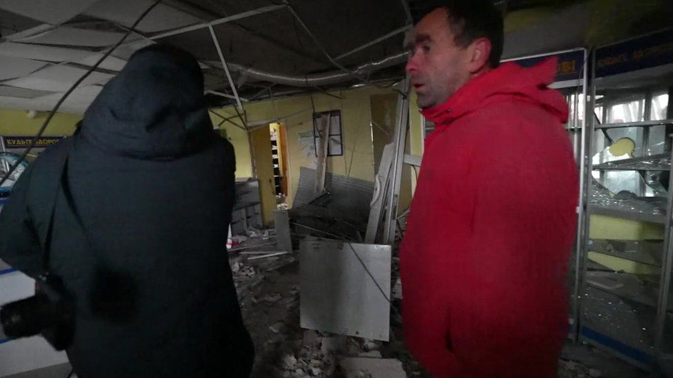Image shows two men in destroyed shop