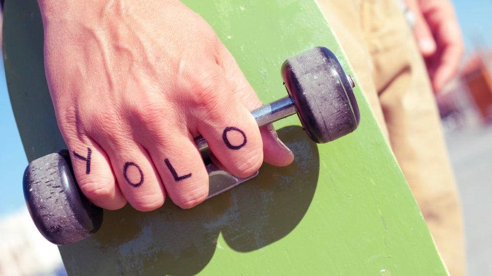 A skateboarder with the word YOLO written on their hand.