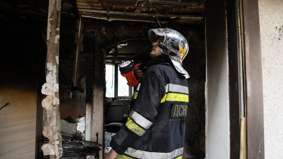 Firefighter with a flashlight inspects burnt residential house after Russian shelling on August 30, 2023 in Tarasivka, Ukraine.