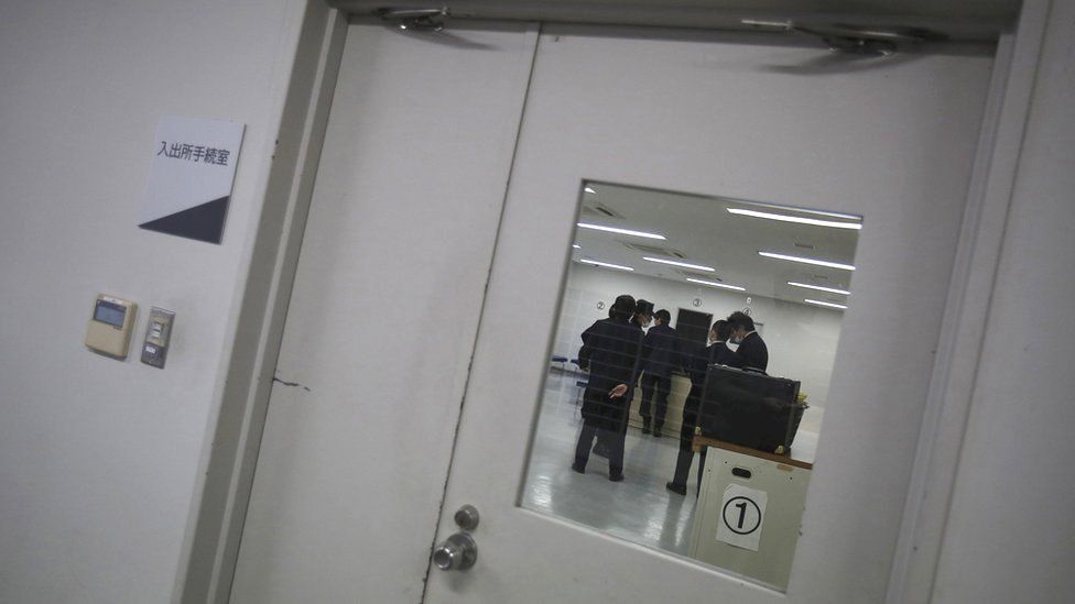 Охранники через окно двери Иммиграционного центра Восточной Японии
