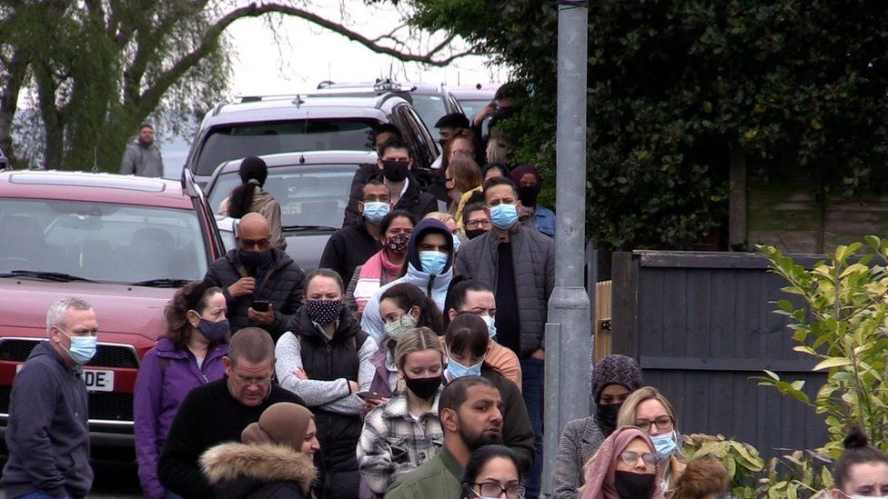 People queue for the vaccination centre at the Essa Academy in Bolton on Friday