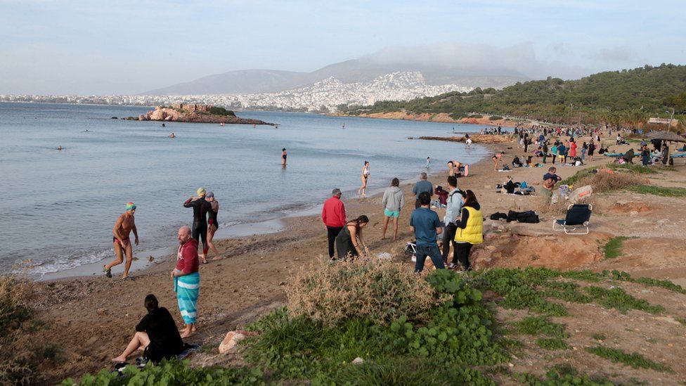 People enjoy the sea at a beach near Athens, Greece, during a warm day while unseasonably high temperatures were seen in the country over the weekend