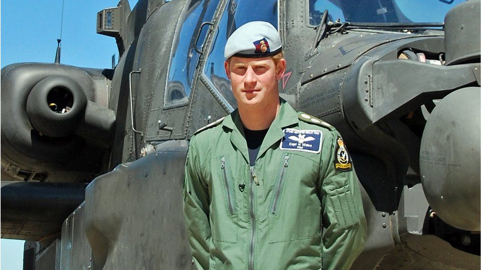 Prince Harry in front of an Apache helicopter