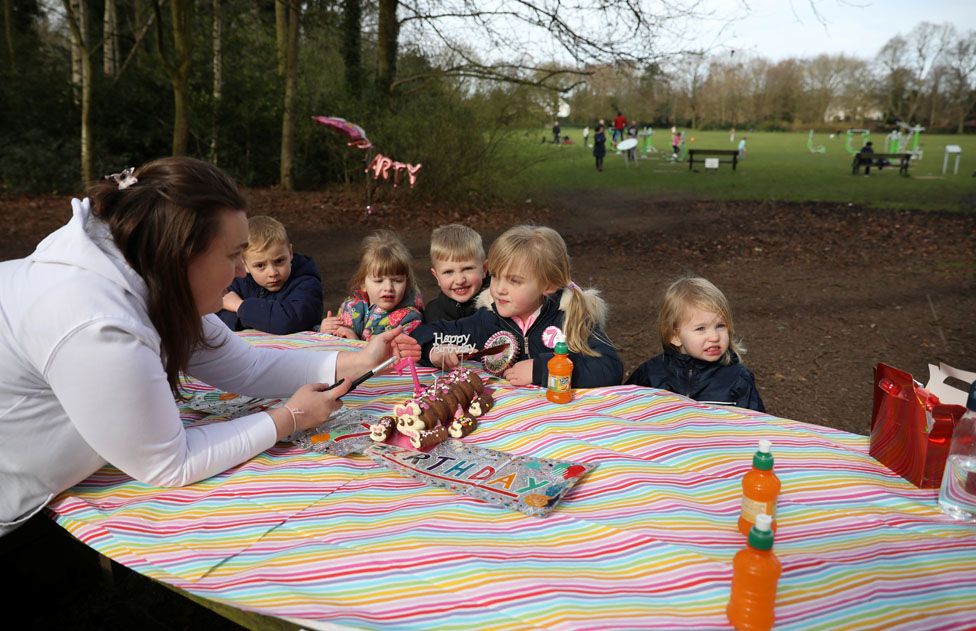 Erin Gatling (C) blows out the candles on her 7th birthday cake as she has an impromptu party in her local park after her original party venue was closed amid the coronavirus disease (COVID-19) outbreak in Manchester