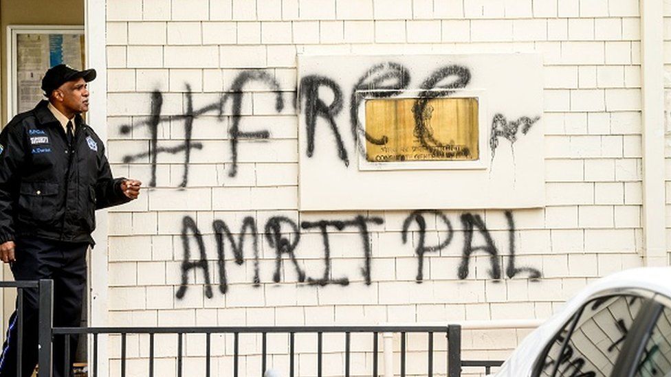 A security guard stands watch at the Indian Consulate as a graffiti behind him reads "FreeAmritpal" in San Francisco, California on 20 March 2023