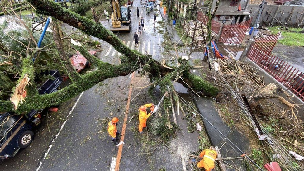 Filipino government workers clear a toppled tree in the typhoon-hit town of Tigaon, Camarines Sur, Philippines, 01 November 2020