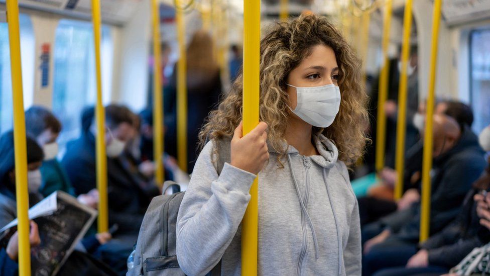 Woman on a Tube train in a mask