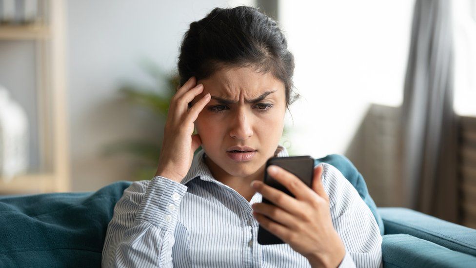 Молодая женщина обеспокоена чем-то в своем телефоне