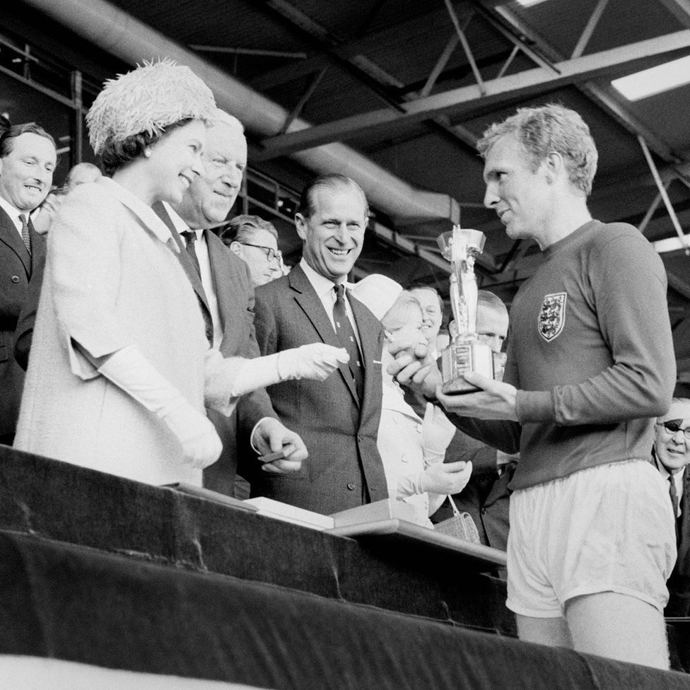 England captain Bobby Moore holds the Jules Rimet Trophy, collected from the Queen Elizabeth II