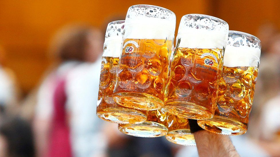 A waiter carries glasses of beer during the opening day of Oktoberfest in Munich