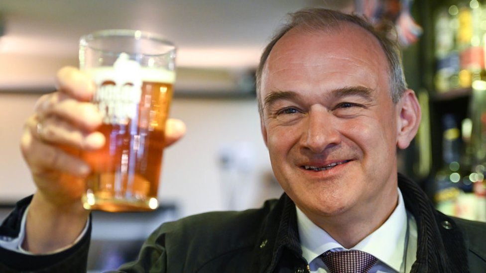 Lib Dem leader Sir Ed Davey lifting up a pint of beer at The George Inn in Windsor