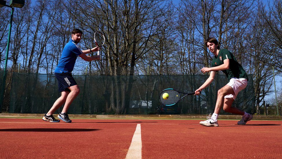 Two people playing tennis outdoors