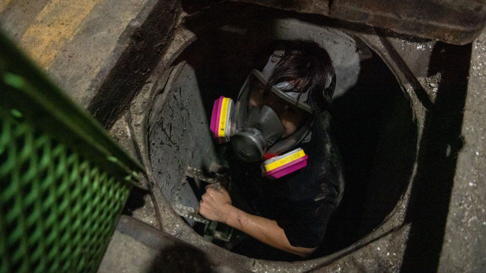 An anti-government protester attempts to escape Hong Kong Polytechnic University by going through a sewer on November 19, 2019