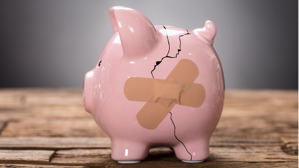 A cracked piggy bank with a plaster across it