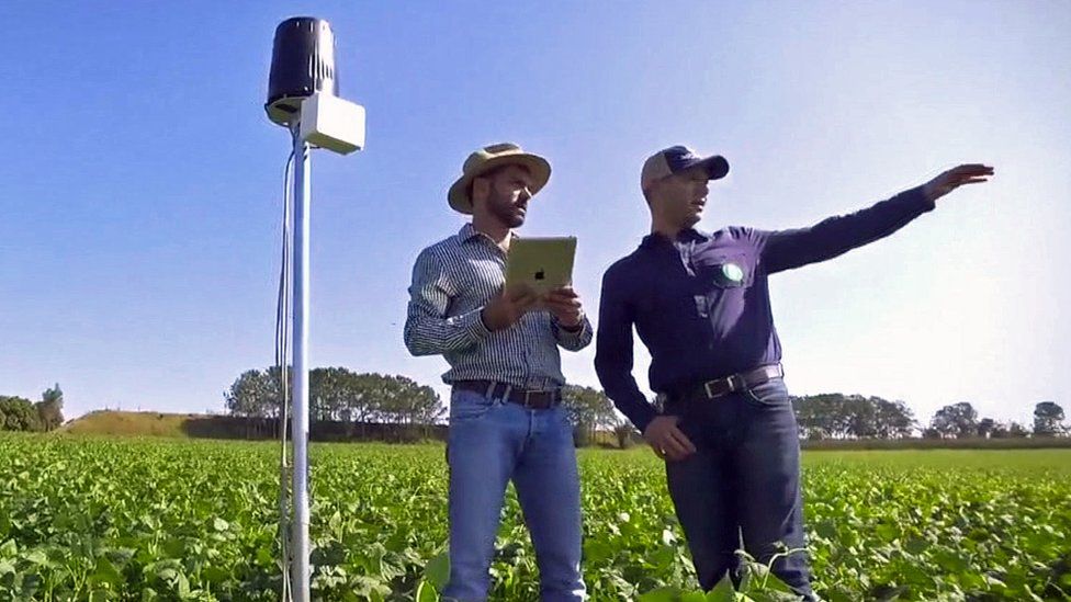 Two men with an Agrosmart sensor in a field